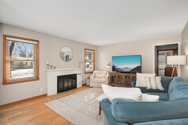 living room with light wood finished floors, a fireplace, and baseboards