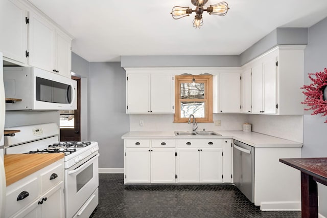 kitchen with light countertops, white appliances, white cabinets, and a sink