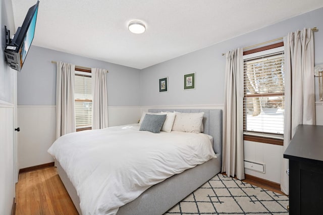 bedroom featuring wainscoting and light wood finished floors