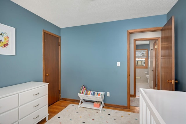 bedroom with a textured ceiling, light wood finished floors, and baseboards