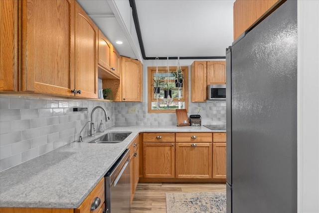 kitchen featuring tasteful backsplash, a sink, light countertops, black appliances, and light wood-style flooring