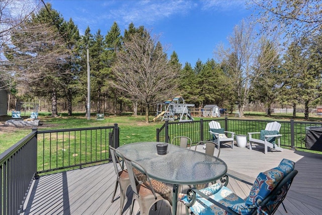 deck featuring a playground, outdoor dining area, and a lawn