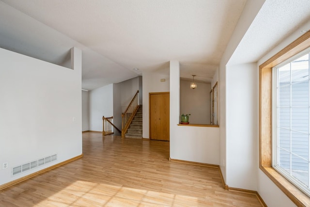 empty room featuring a textured ceiling and light hardwood / wood-style flooring