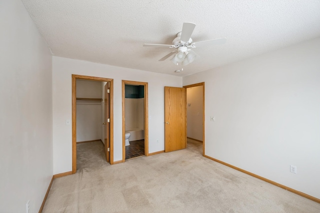 unfurnished bedroom with ceiling fan, a textured ceiling, light carpet, a spacious closet, and a closet