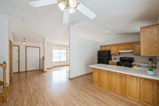 kitchen with lofted ceiling, sink, light wood-type flooring, kitchen peninsula, and black appliances