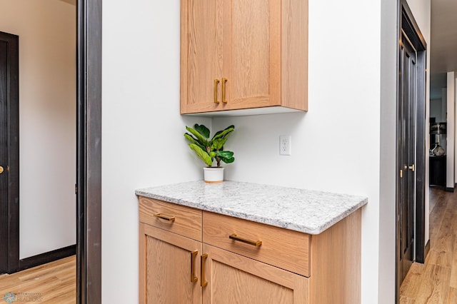 kitchen with light wood-type flooring and light stone countertops