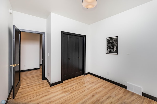 unfurnished bedroom with light wood-type flooring and a closet