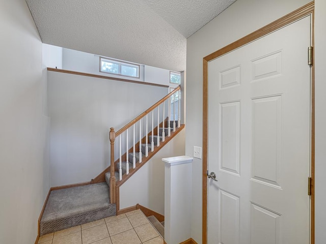 staircase featuring tile patterned floors and a textured ceiling