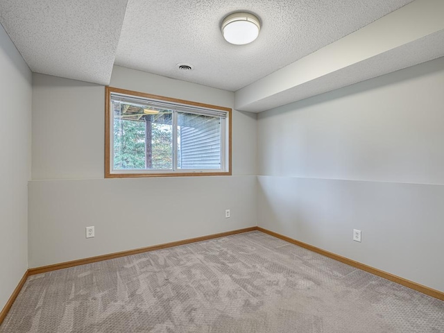 empty room with light colored carpet and a textured ceiling