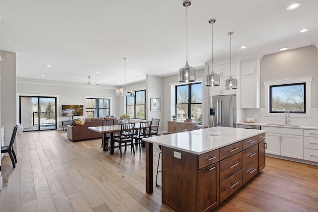 kitchen with white cabinets, a center island, high quality fridge, and decorative light fixtures