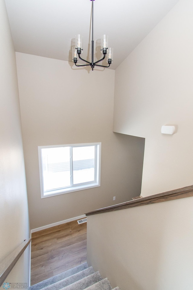 stairway with wood-type flooring and a chandelier