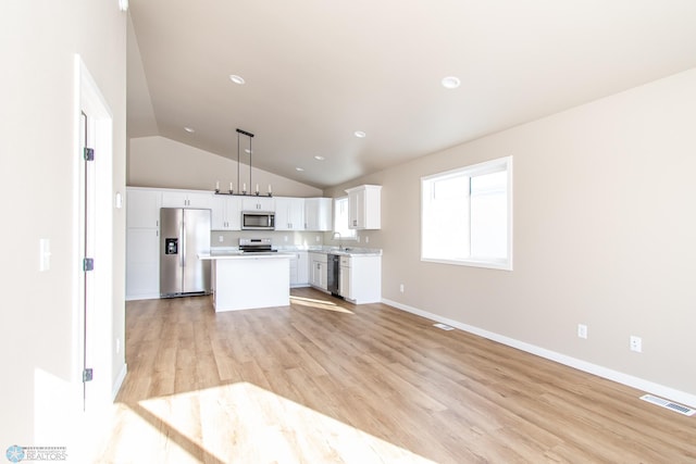 kitchen featuring sink, stainless steel appliances, white cabinets, a kitchen island, and decorative light fixtures