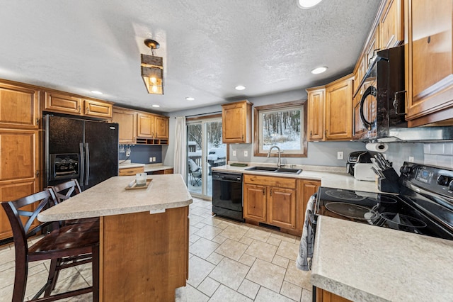 kitchen with sink, a kitchen bar, hanging light fixtures, a center island, and black appliances