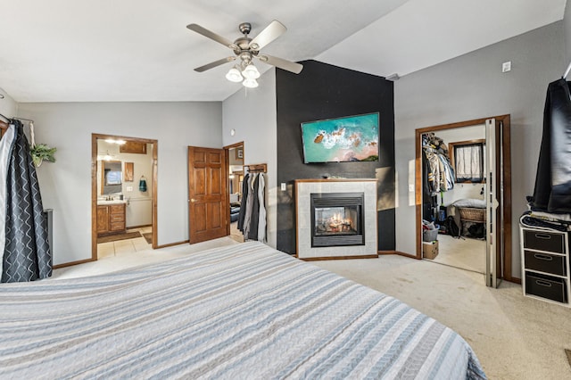 bedroom with a walk in closet, vaulted ceiling, light carpet, a closet, and a tile fireplace