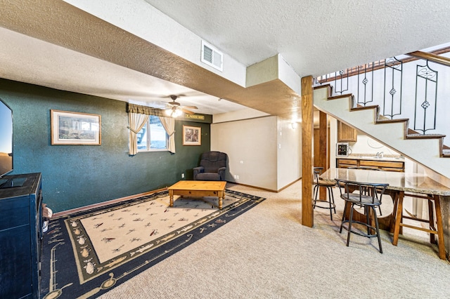 interior space with ceiling fan, light colored carpet, and a textured ceiling