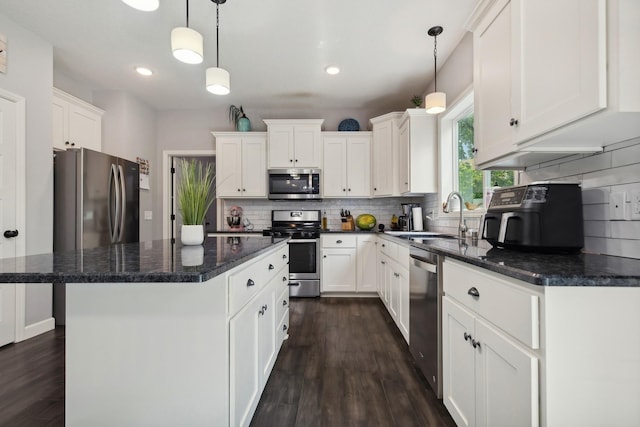 kitchen with tasteful backsplash, decorative light fixtures, a center island, appliances with stainless steel finishes, and white cabinets