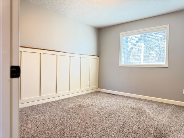 carpeted spare room with a textured ceiling