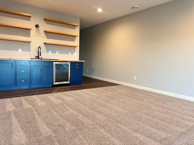 bar featuring blue cabinetry, sink, beverage cooler, and dark carpet