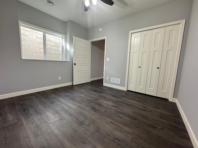 unfurnished bedroom with dark hardwood / wood-style floors, ceiling fan, and a closet