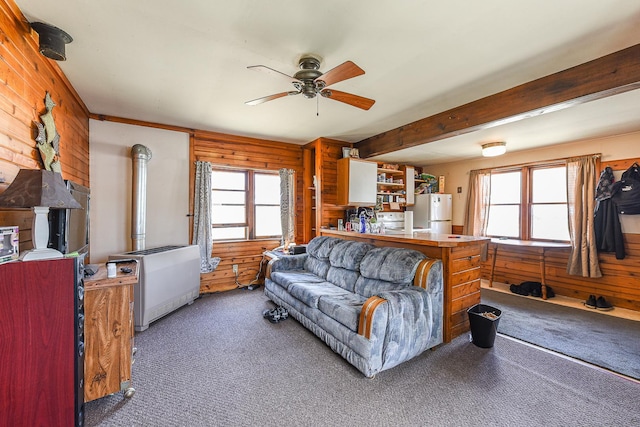 living room featuring plenty of natural light, wooden walls, and dark colored carpet