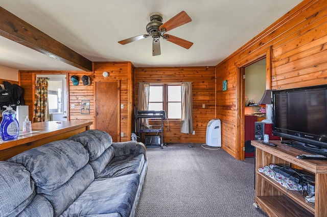 carpeted living room featuring ceiling fan, wooden walls, and beamed ceiling