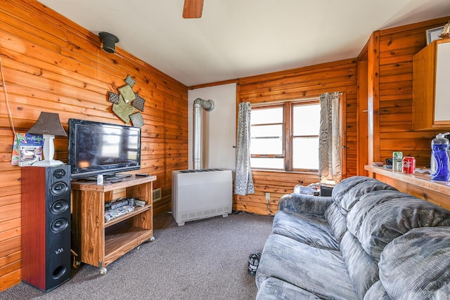 living room with wooden walls, heating unit, and dark colored carpet