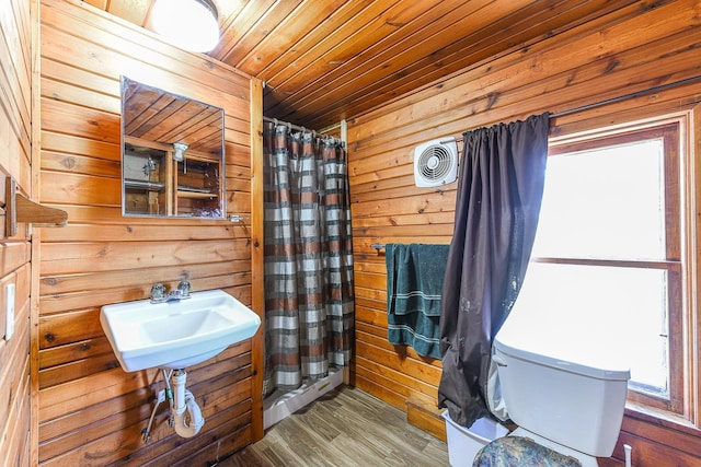 bathroom with sink, hardwood / wood-style flooring, wooden ceiling, and wood walls