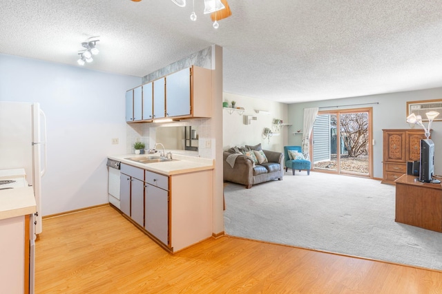 kitchen with open floor plan, white appliances, light countertops, and a sink