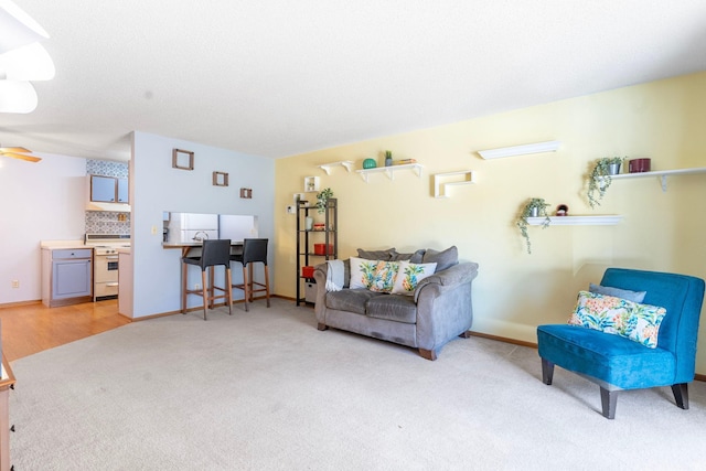 living area featuring light carpet and baseboards