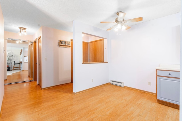 unfurnished room with a baseboard heating unit, baseboards, light wood-style flooring, a textured ceiling, and a ceiling fan