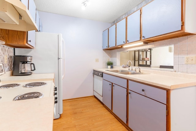 kitchen with white appliances, a sink, light countertops, a textured ceiling, and light wood-type flooring