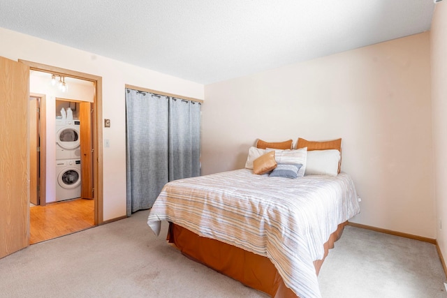 bedroom featuring stacked washer / dryer, baseboards, and light carpet