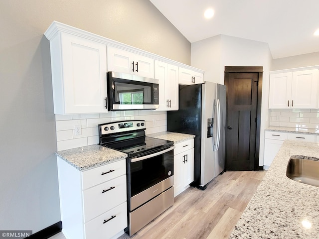 kitchen with stainless steel appliances, white cabinetry, and light stone countertops