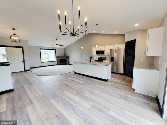 kitchen featuring light stone counters, stainless steel appliances, decorative light fixtures, and white cabinets