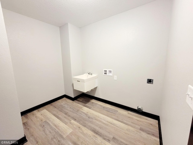 laundry room with sink, light hardwood / wood-style flooring, a textured ceiling, washer hookup, and hookup for an electric dryer