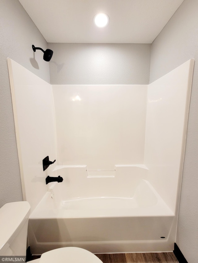 bathroom featuring bathtub / shower combination, wood-type flooring, and toilet