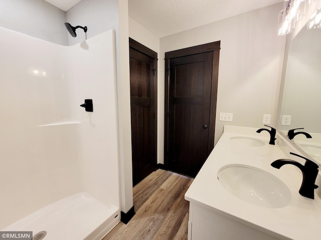 bathroom featuring vanity, a shower, wood-type flooring, and a textured ceiling