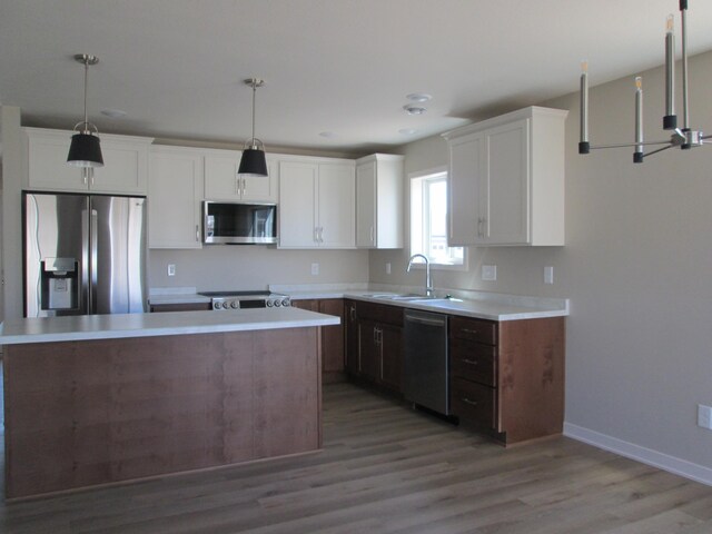 426 Fawn Run, Kenyon, MN 55946 - kitchen featuring appliances with stainless steel finishes, light wood finished floors, white cabinetry, light countertops, and decorative light fixtures