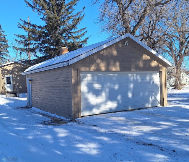 snow covered garage with a detached garage