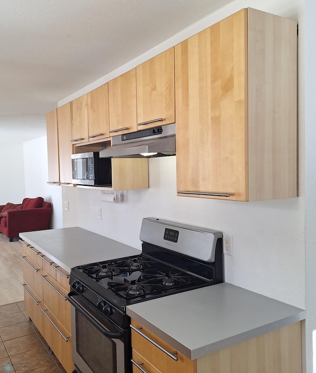 kitchen featuring stainless steel appliances, a textured ceiling, light countertops, under cabinet range hood, and light brown cabinets