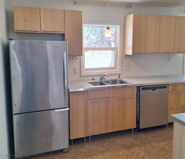 kitchen with stainless steel appliances, a sink, hanging light fixtures, light countertops, and light brown cabinetry