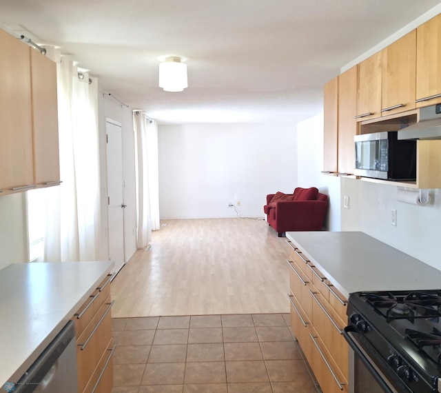 kitchen with light brown cabinets, stainless steel appliances, light countertops, and light tile patterned flooring