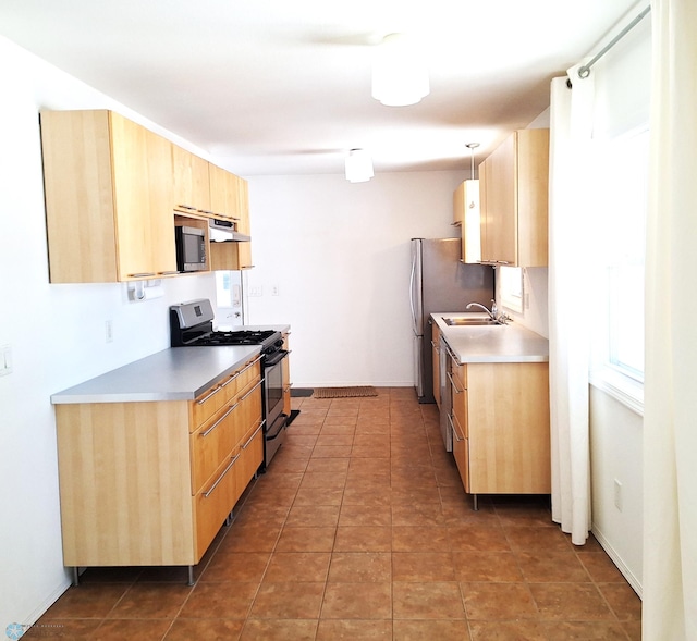 kitchen featuring light brown cabinets, appliances with stainless steel finishes, light countertops, and a sink