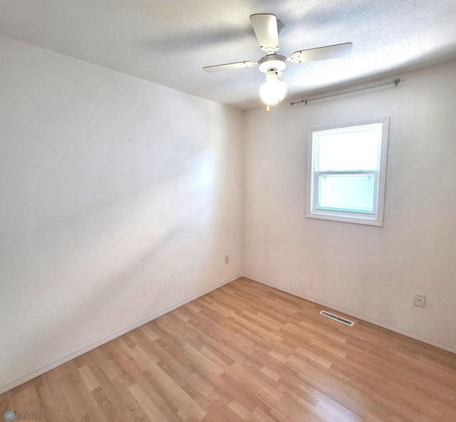 empty room featuring a ceiling fan, light wood-type flooring, visible vents, and baseboards