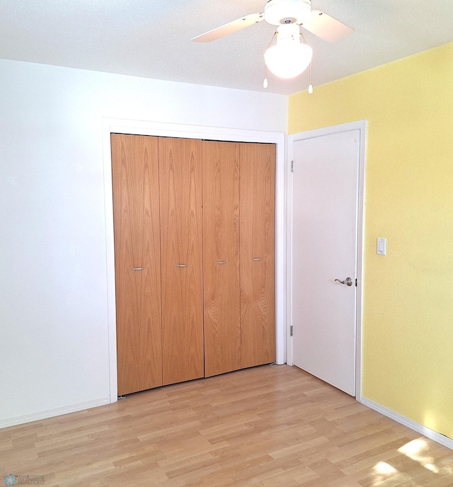 unfurnished bedroom featuring baseboards, a closet, light wood-style flooring, and a ceiling fan