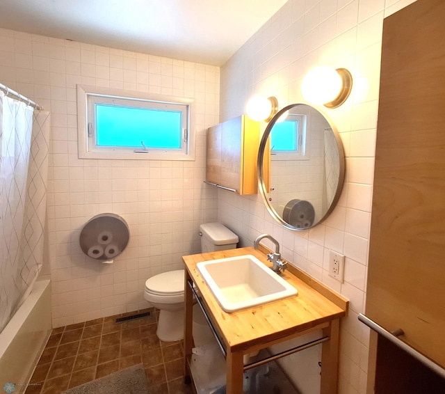 bathroom featuring plenty of natural light, visible vents, toilet, tile patterned flooring, and tile walls