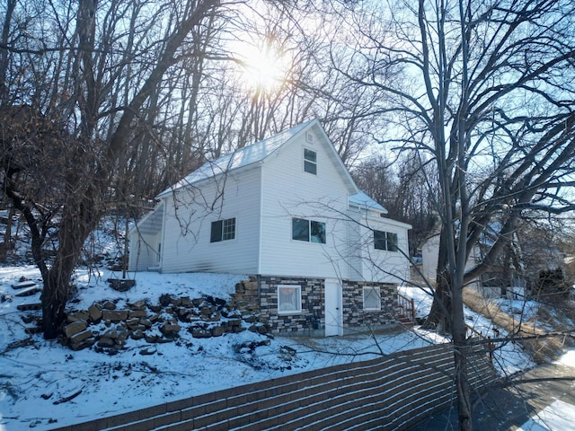 view of snowy exterior with stone siding