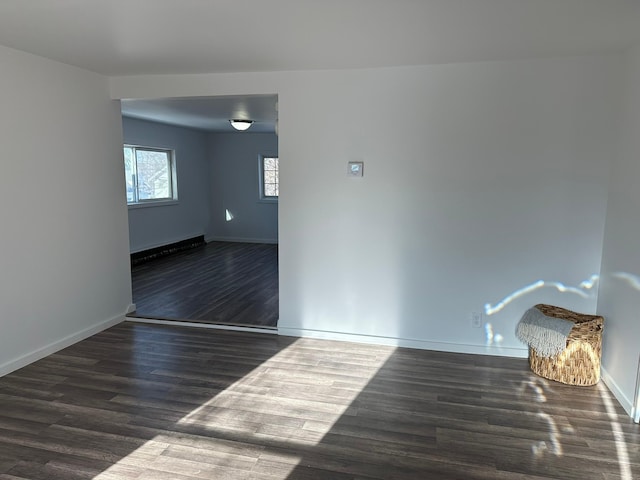 spare room with dark wood-style flooring and baseboards