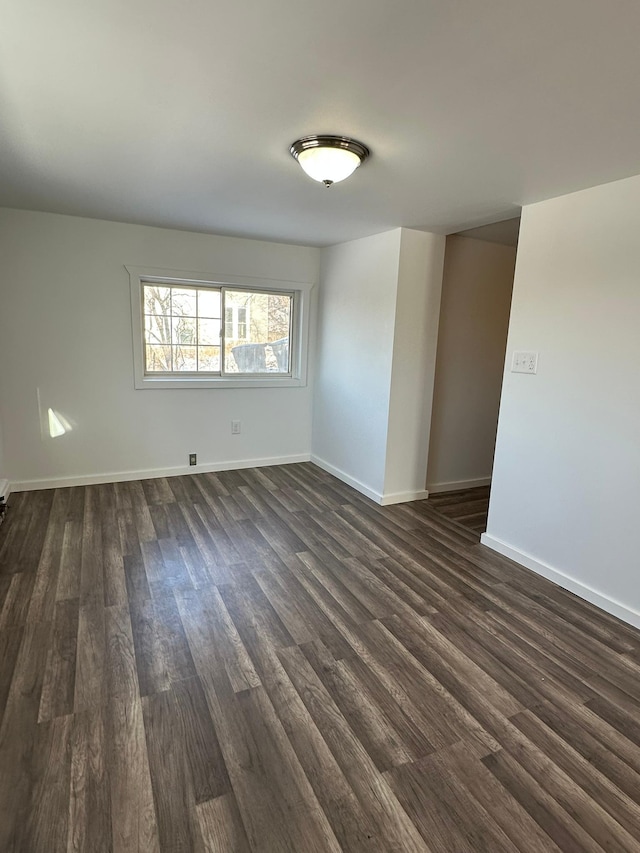 spare room with baseboards and dark wood finished floors