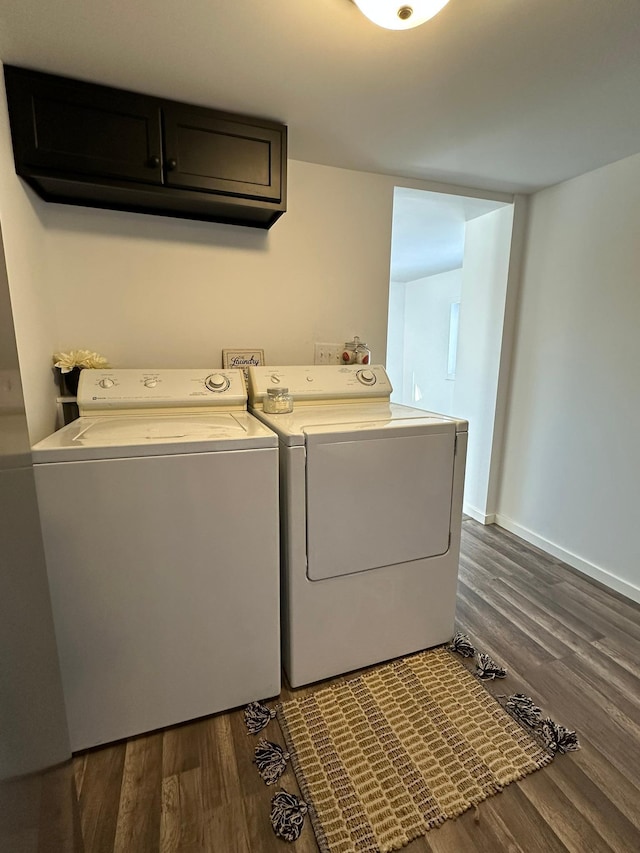 laundry area featuring wood finished floors, washing machine and dryer, cabinet space, and baseboards